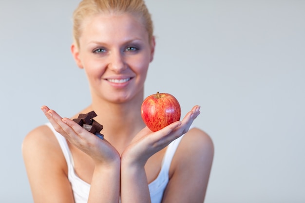 Mulher atraente que mostra chocolate e maçã foco em chocolate e maçã