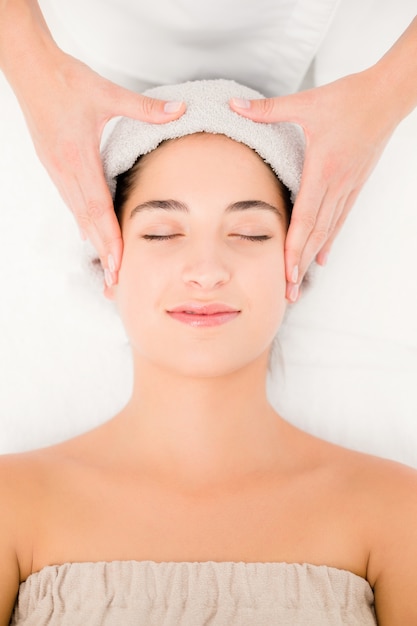 Mulher atraente que recebe massagem facial no centro de spa