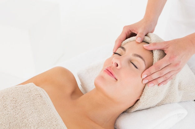 Mulher atraente que recebe massagem facial no centro de spa
