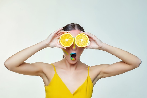 Mulher atraente segurando fatias de laranja na frente do rosto