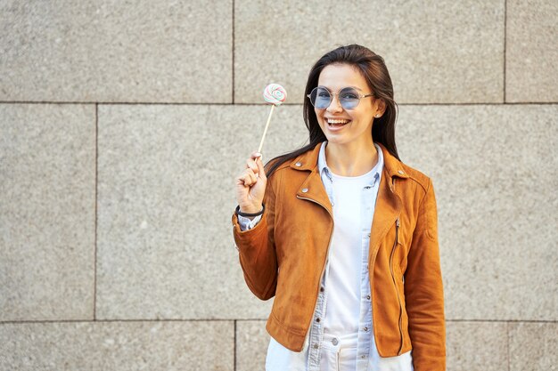 Foto mulher atraente sorridente de óculos de sol, posando para a câmera