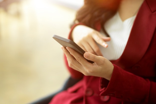 Mulher atraente usando gadget de telefone celular rolando em mensagens de mídia social para compras online