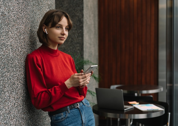 Mulher atraente usando telefone celular, planejando o projeto de inicialização