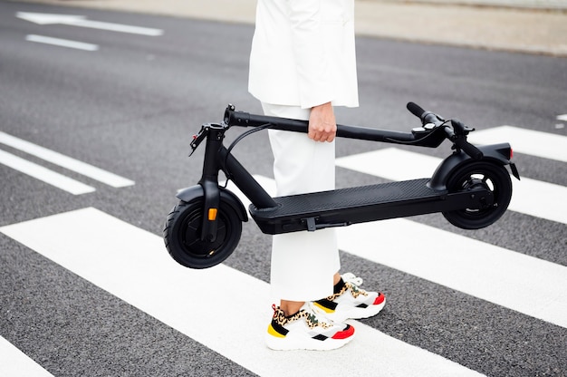 Mulher atravessando a rua com uma scooter elétrica