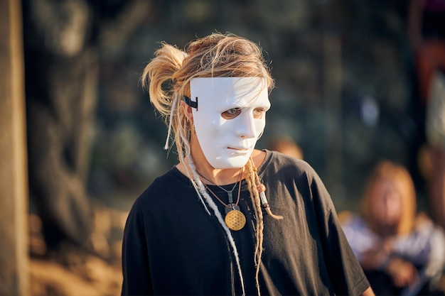 Mulher atuando em persona de palco em máscara de teatro no rosto performance de arte de palco ao ar livre Atriz de teatro de menina em estilo preto total faz movimentos suaves no papel de palco Festival de performance teatral