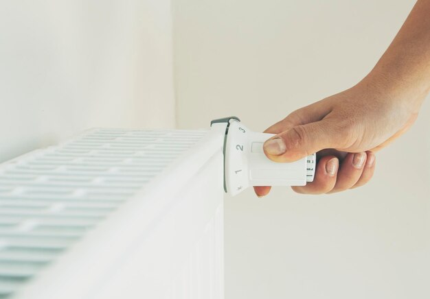 Mulher aumenta a temperatura do radiador ajustando o termostato