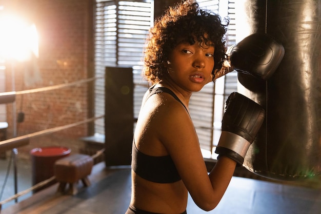 Foto mulher autodefesa girl power lutadora afro-americana descansando após treinamento de luta no boxe