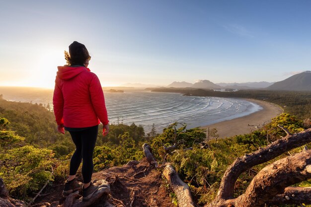 Foto mulher aventureira alpinista com vista para a praia arenosa na costa oeste do oceano pacífico