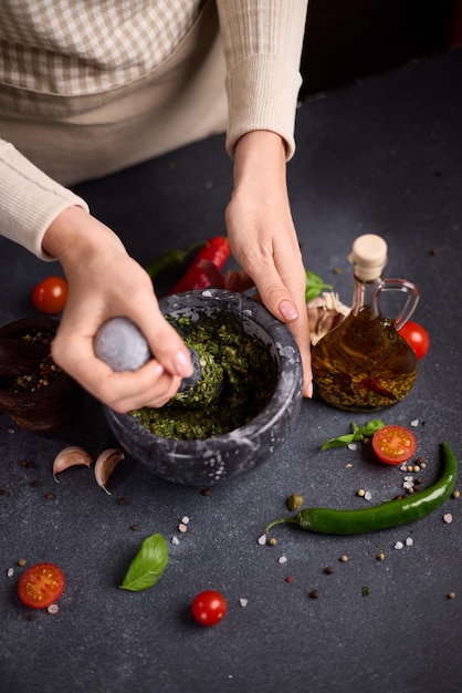 Foto mulher batendo em uma pedra mármore argamassa molho verde ingredientes picados capers erva-doce e manjericão