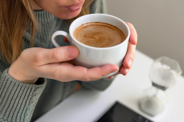 Mulher bebendo café e usando laptop tablet digital
