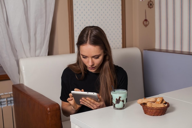 Mulher bebendo chá e usando tablet