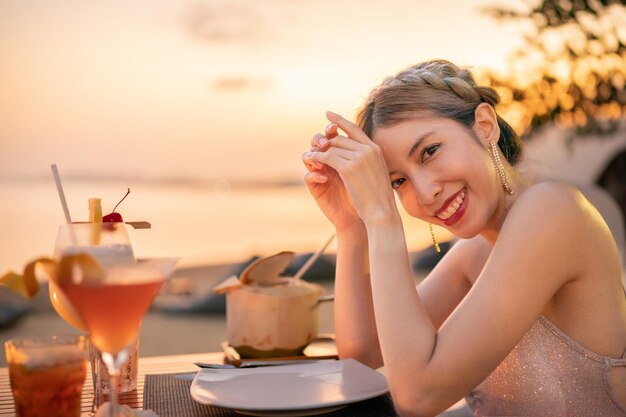 Foto mulher bebendo coquetéis na praia, momento romântico do pôr do sol, férias de verão