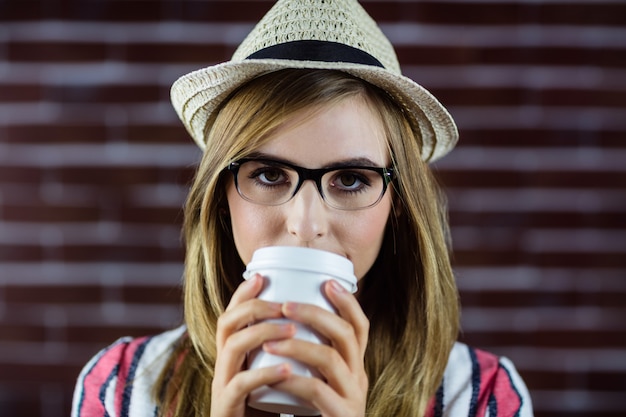 Mulher bebendo uma bebida e usando um chapéu