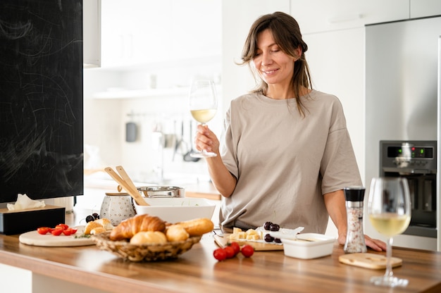 Mulher bebendo uma taça de vinho na cozinha