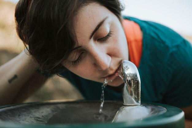 Mulher beber água de uma fonte de água