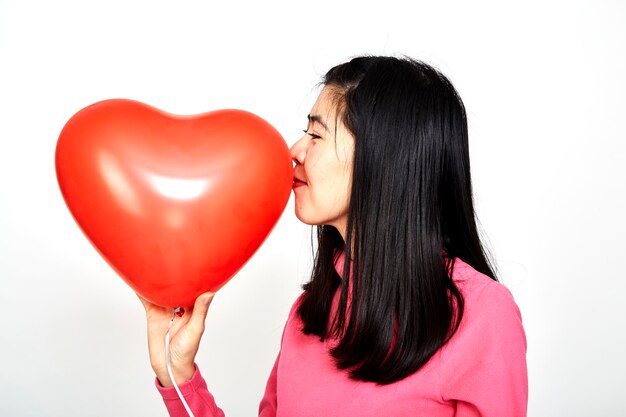 Foto mulher beijando balão em forma de coração contra fundo branco