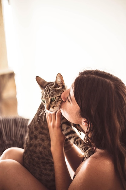 Mulher beijando gato em casa