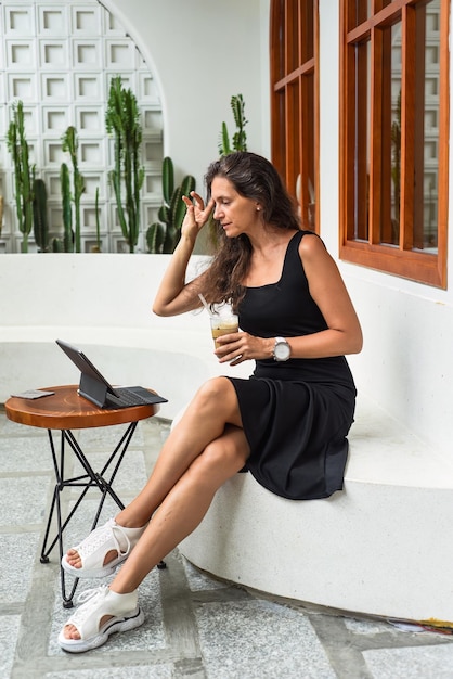 Mulher bem-sucedida de 40 anos sentada em um café e escrevendo em seu tablet com caneta stylus