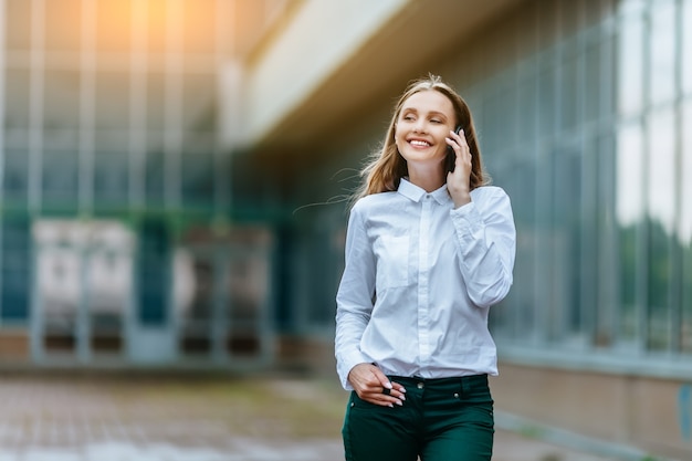 mulher bem-sucedida falando ao telefone ao ar livre de um prédio de escritórios