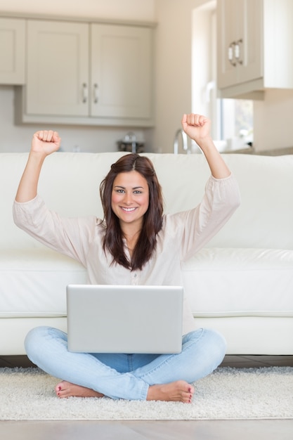 Mulher bem sucedida levantando as mãos na frente do laptop