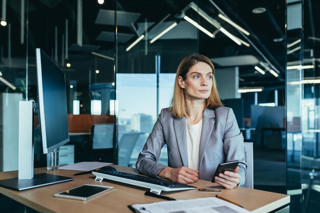 Mulher bem sucedida que trabalha em um escritório moderno em uma empresária de computador usa as redes sociais do telefone navegando on-line