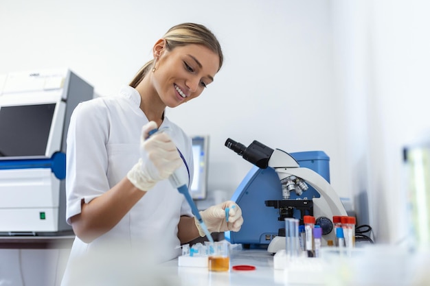 Mulher bióloga usando micro pipeta com tubo de ensaio e copo para experimento em laboratório de ciências Especialista em bioquímica trabalhando com equipamentos de laboratório e vidraria para desenvolvimento