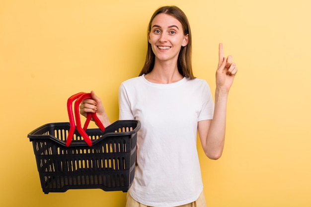 Mulher bonita adulta jovem segurando uma cesta de compras vazia