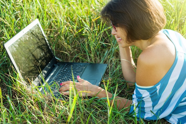 Mulher bonita adulta usando laptop na natureza