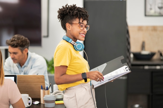 Mulher bonita afro-americana com fones de ouvido e óculos, vista em coworking Mulher bonita afro-americana com fones de ouvido e óculos, vista em coworking