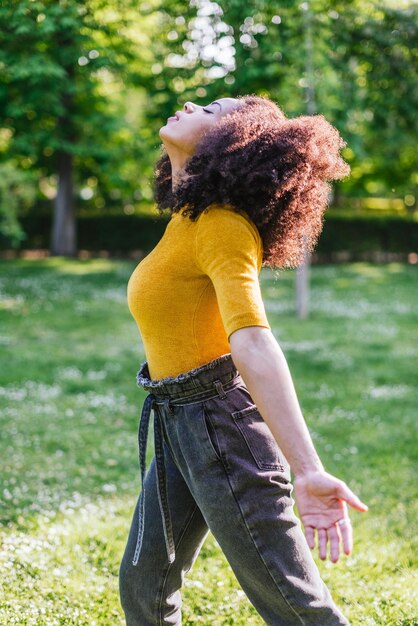 Mulher bonita afro, respirando ar fresco na natureza, em um jardim. Foco seletivo.