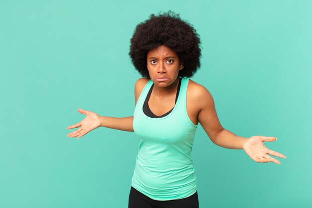 mulher bonita afro vestindo roupas de ginástica contra uma parede isolada