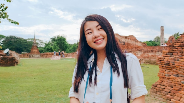 Foto mulher bonita alegre jovem mochileiro asiática com uma câmera tirando uma foto, viajando pelo pagode na cidade velha