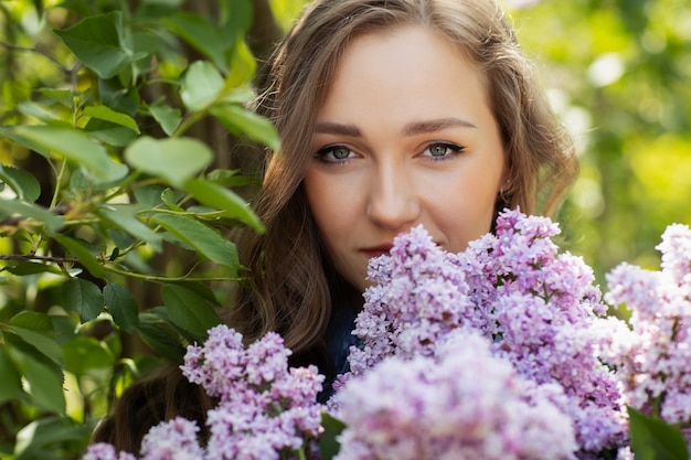 Mulher bonita, apreciando o cheiro de lilás. Modelo bonito e flores. Aromaterapia e conceito de primavera Uma garota com cabelo comprido. Flor lilás de primavera