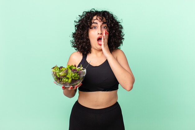 Mulher bonita árabe se sentindo chocada e com medo e segurando uma salada. conceito de dieta