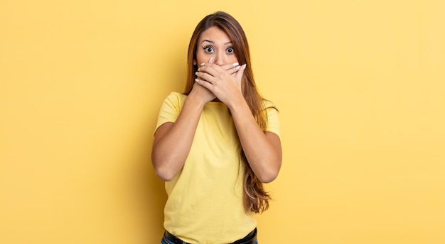 Mulher bonita asiática cobrindo a boca com as mãos com uma expressão chocada e surpresa, mantendo um segredo ou dizendo oops