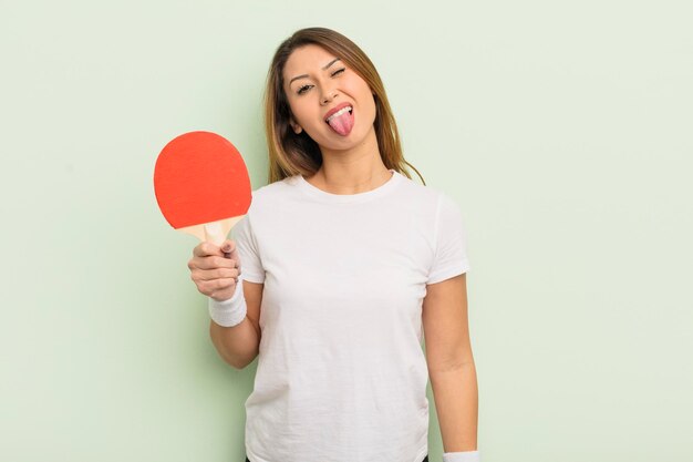 Mulher bonita asiática com atitude alegre e rebelde brincando e enfiando a língua para fora do conceito de pingue-pongue