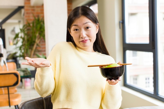 Mulher bonita asiática comendo uma tigela de macarrão ramen