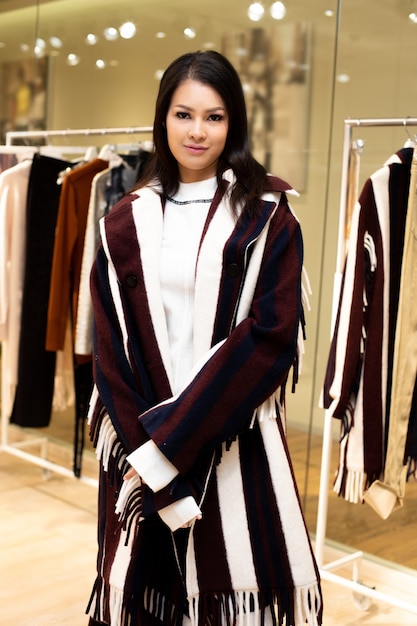 Mulher bonita asiática em vestido preto branco seleciona nova coleção em cabideiro pronto para usar em loja de moda de varejo que acaba de abrir as novidades do inverno outono como estilo casual