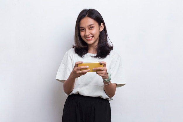 Mulher bonita asiática jovem feliz usando telefone celular isolado no fundo branco