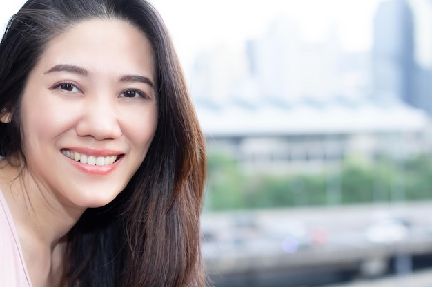 Mulher bonita asiática olhando para a câmera com sorriso e felicidade em seu dia de lazer