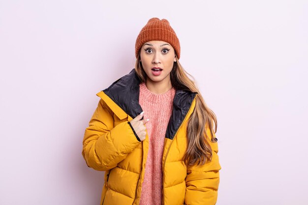 Mulher bonita asiática parecendo chocada e surpresa com a boca aberta, apontando para si mesma. conceito de inverno