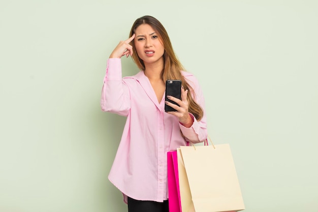 Mulher bonita asiática se sentindo confusa e confusa, mostrando que você é louco. conceito de sacolas de compras