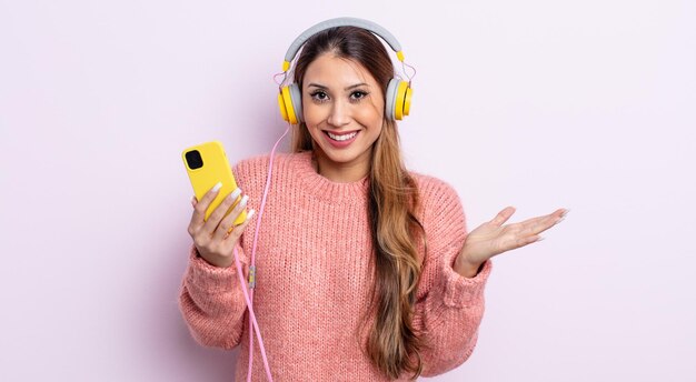 Mulher bonita asiática se sentindo feliz e surpresa com algo inacreditável. fones de ouvido e conceito de telefone