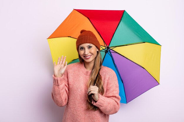 Mulher bonita asiática sorrindo alegremente, acenando com a mão, dando as boas-vindas e cumprimentando você. conceito de guarda-chuva