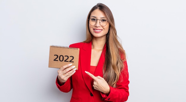 Mulher bonita asiática sorrindo alegremente, sentindo-se feliz e apontando para o lado. conceito de calendário