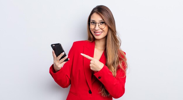 Mulher bonita asiática sorrindo alegremente, sentindo-se feliz e apontando para o lado. conceito de negócios e telefone.