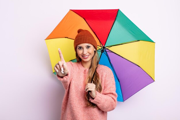 Mulher bonita asiática sorrindo e parecendo amigável, mostrando o número um. conceito de guarda-chuva