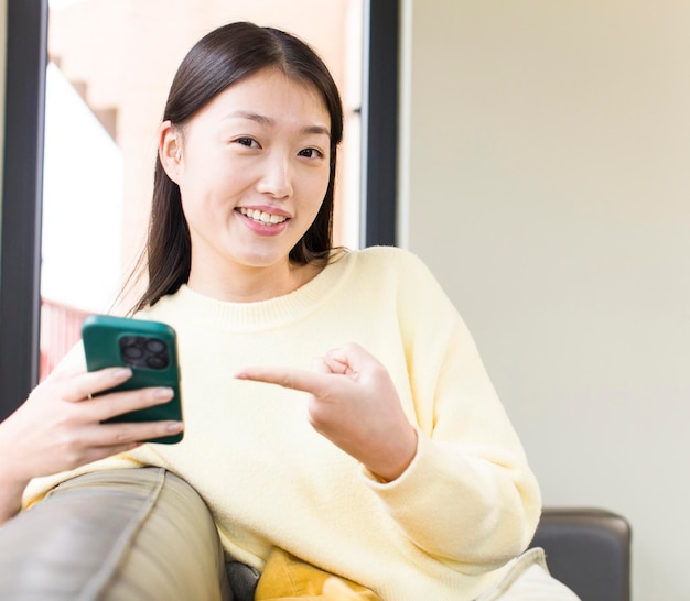 Mulher bonita asiática usando um smartphone e fazendo compras em casa