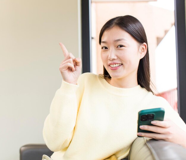 Mulher bonita asiática usando um smartphone e fazendo compras em casa