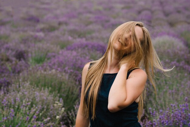 Mulher bonita caminhada engraçada no campo de lavanda no pôr do sol Linda garota de vestido e cabelos longos voando no campo de lavanda roxo Foco suave Aprecie a natureza floral do verão da clareira Penteado